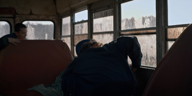 Wide shot frame from Stranger Things — sitting, car, train