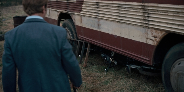 Wide shot frame from Stranger Things — standing, hand, suit