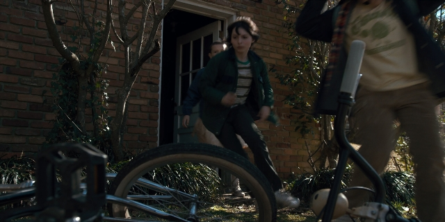 Wide shot frame from Stranger Things — walking, door, hand