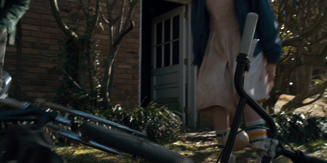Wide shot frame from Stranger Things — standing, door, bicycle