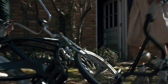 Wide shot frame from Stranger Things — standing, door, bicycle