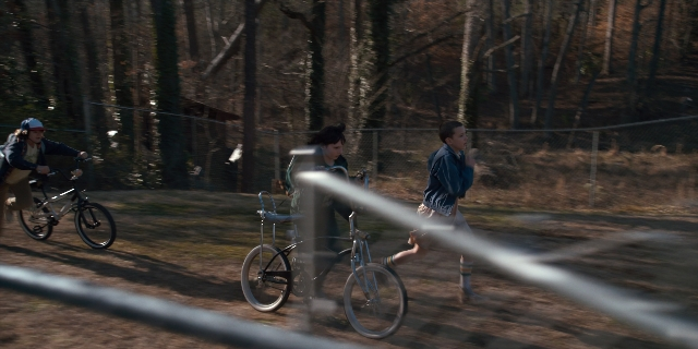 Wide shot frame from Stranger Things — bicycle, person, human face