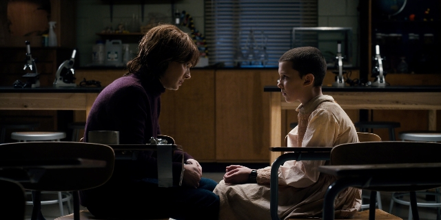 Wide shot frame from Stranger Things — sitting, book, room