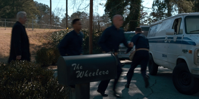 Wide shot frame from Stranger Things — walking, street, van