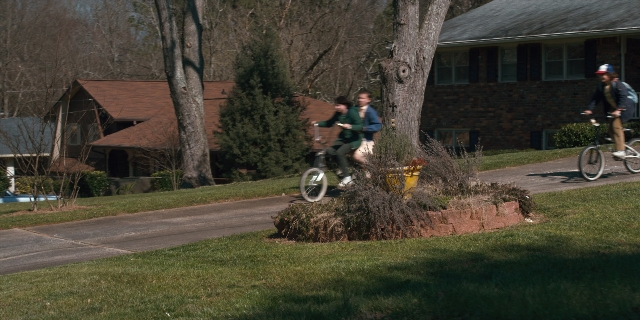 Wide shot frame from Stranger Things — street, house, bicycle