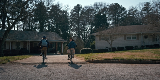 Wide shot frame from Stranger Things — house, bicycle, person