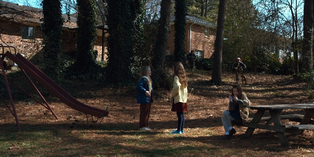 Wide shot frame from Stranger Things — sitting, standing, walking