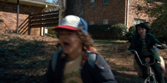 Medium shot frame from Stranger Things — hat, bicycle, jacket