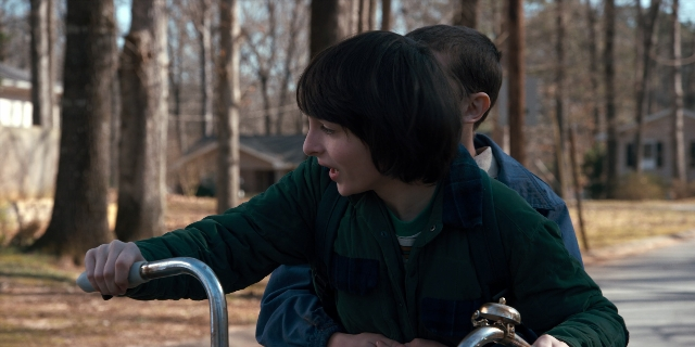Wide shot frame from Stranger Things — dialogue, street, bicycle