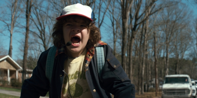 Wide shot frame from Stranger Things — standing, street, hat