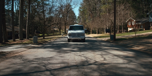 Wide shot frame from Stranger Things — street, house, truck