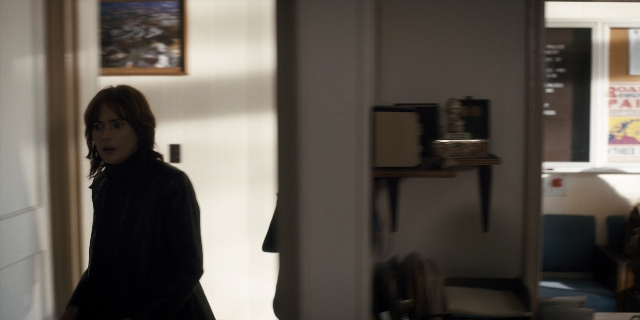 Wide shot frame from Stranger Things — standing, coat, chair