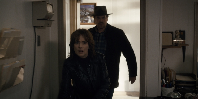 Wide shot frame from Stranger Things — walking, door, hat