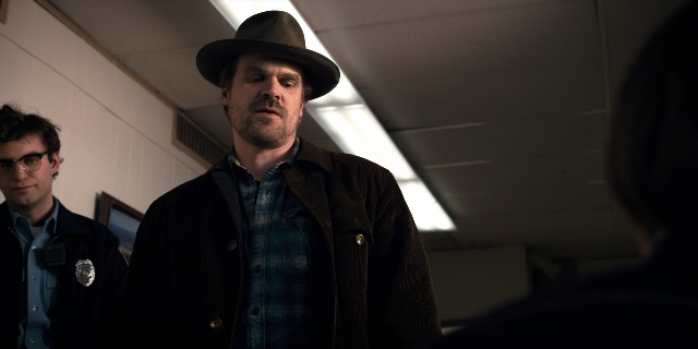 Wide shot frame from Stranger Things — standing, hat, jacket