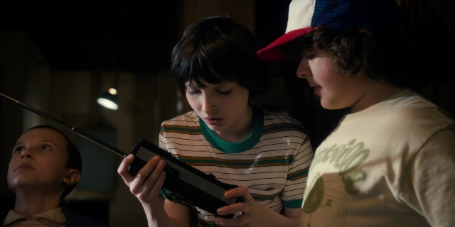 Wide shot frame from Stranger Things — standing, room, hat