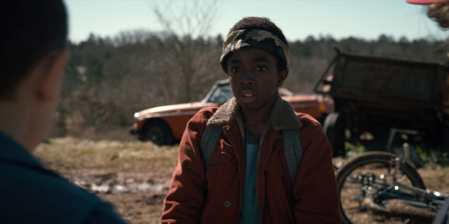 Wide shot frame from Stranger Things — standing, dialogue, hat