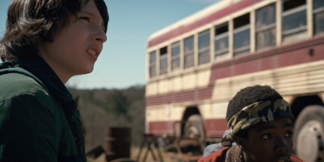Wide shot frame from Stranger Things — standing, bus, face