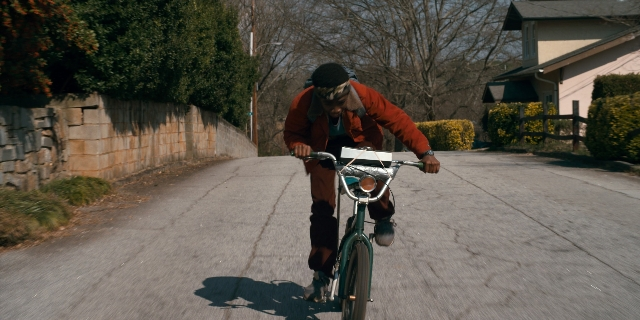 Wide shot frame from Stranger Things — street, bicycle, person