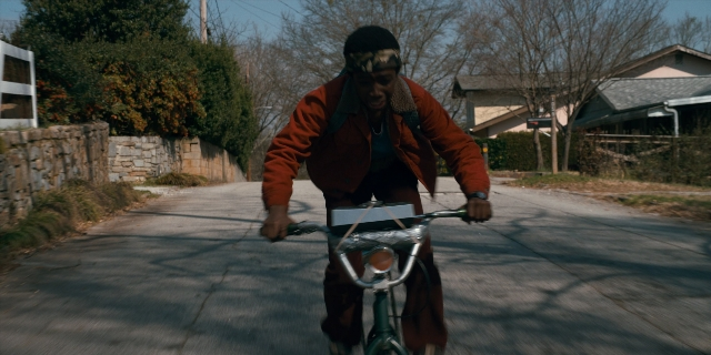 Wide shot frame from Stranger Things — street, bicycle, person