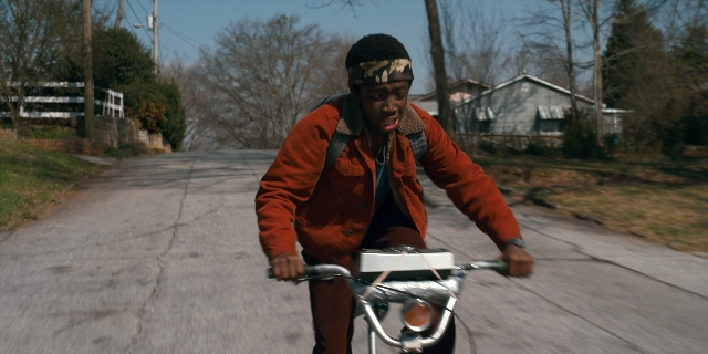 Wide shot frame from Stranger Things — street, bicycle, jacket