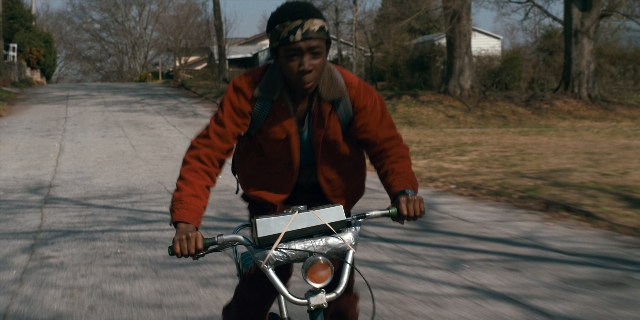Wide shot frame from Stranger Things — street, bicycle, jacket