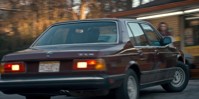 Wide shot frame from Stranger Things — plate, street, car