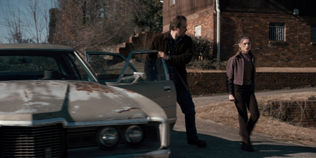 Wide shot frame from Stranger Things — walking, door, street