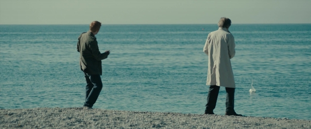 Medium shot frame from About Time — standing, phone, coat