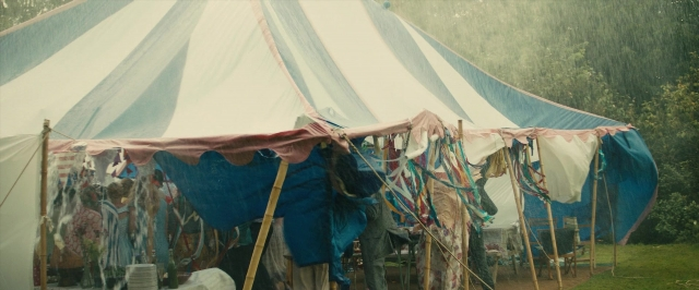 Wide shot frame from About Time — standing, table, tent