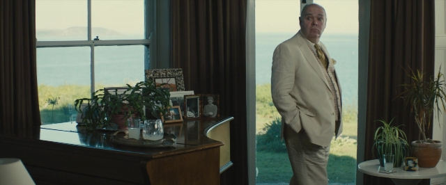 Wide shot frame from About Time — standing, table, suit