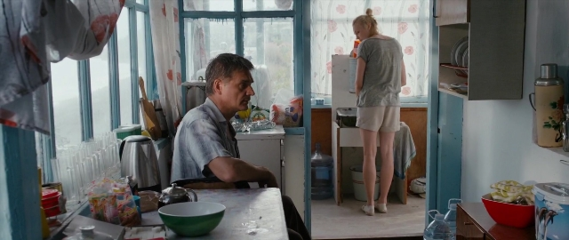 Wide shot frame from Kak menya zovut — sitting, standing, table