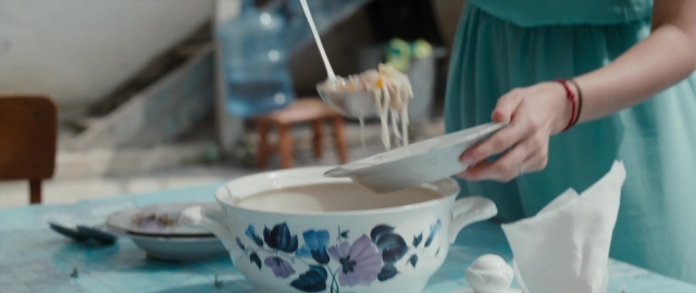 Wide shot frame from Kak menya zovut — sitting, table, bowl