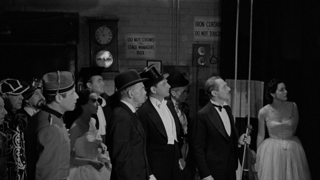 Wide shot frame from Limelight — standing, room, hat