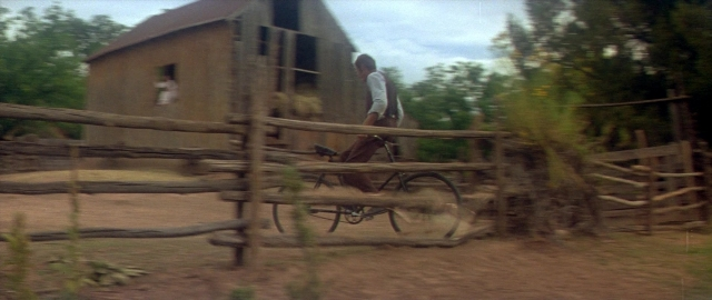 Wide shot frame from Butch Cassidy and the Sundance Kid — street, house, bicycle