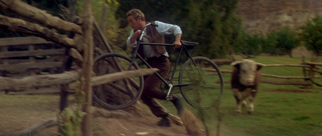 Wide shot frame from Butch Cassidy and the Sundance Kid — walking, dog, bicycle