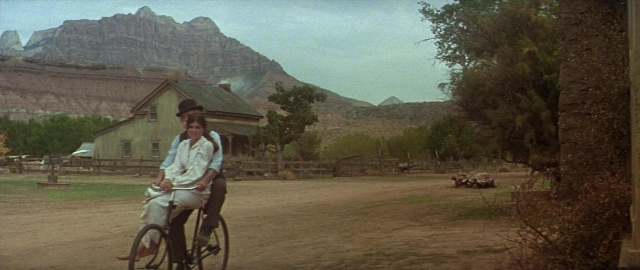 Wide shot frame from Butch Cassidy and the Sundance Kid — sitting, hat, bicycle