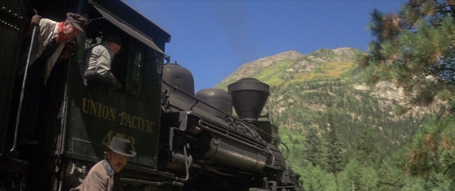 Wide shot frame from Butch Cassidy and the Sundance Kid — standing, hat, train
