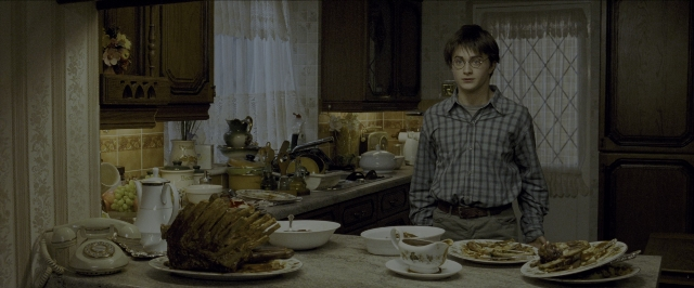 Wide shot frame from Harry Potter and the Prisoner of Azkaban — standing, phone, kitchen