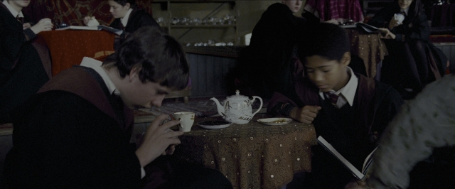 Wide shot frame from Harry Potter and the Prisoner of Azkaban — sitting, book, plate