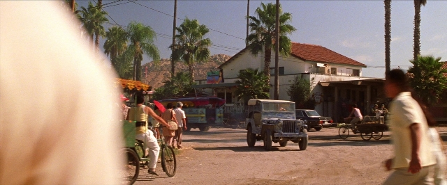Wide shot frame from Man on the Moon — walking, street, bicycle