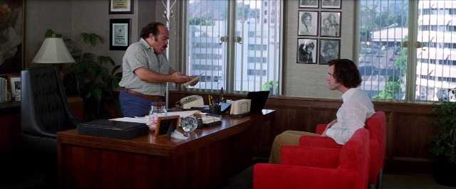 Wide shot frame from Man on the Moon — sitting, desk, standing