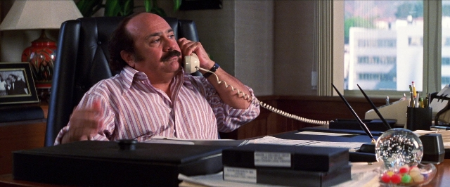 Wide shot frame from Man on the Moon — sitting, desk, dialogue