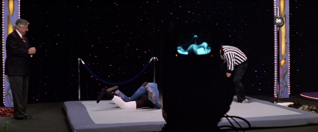 Frame from Man on the Moon — standing, dialogue, bed