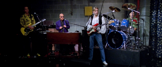 Wide shot frame from Man on the Moon — standing, guitar, drum
