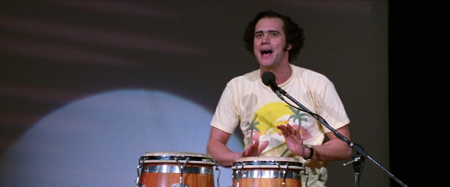 Wide shot frame from Man on the Moon — standing, shirt, microphone