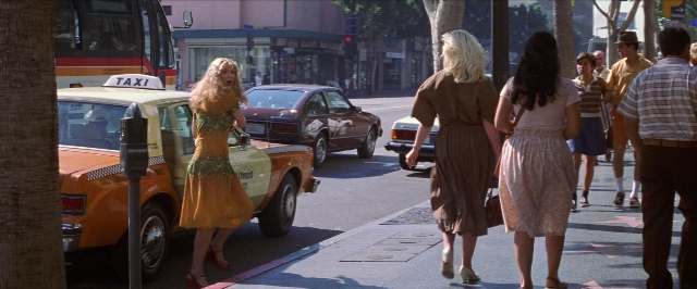 Wide shot frame from Man on the Moon — walking, street, car