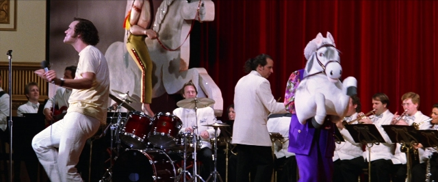 Wide shot frame from Man on the Moon — standing, suit, horse
