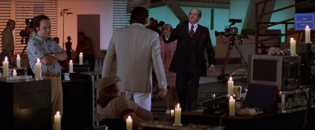 Wide shot frame from Man on the Moon — standing, room, table