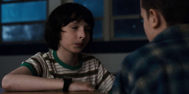 Wide shot frame from Stranger Things — sitting, room, table