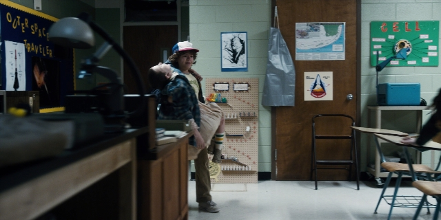 Wide shot frame from Stranger Things — sitting, desk, room